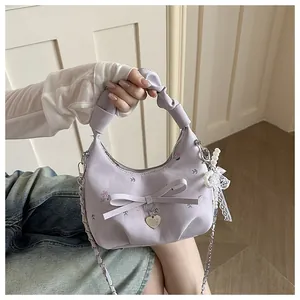 Détail d'un sac à main plissé lilas avec nœud, pendentif cœur et breloque en dentelle