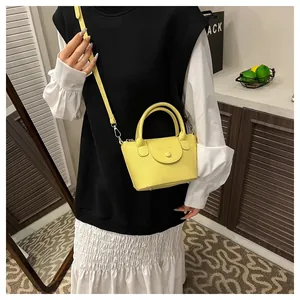 Detailed view of yellow pebbled leather handbag with round buckle and metal feet