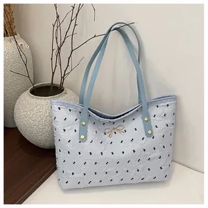 Détail du sac cabas bleu clair texturé avec nœuds noirs et boucle métallique dorée