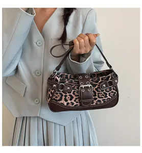 Macro detail of leopard print fabric with brown leather strap and silver metal rivets