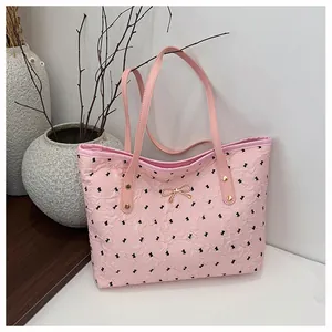 Détail du sac cabas rose à texture bulle avec nœuds noirs et pendentif doré