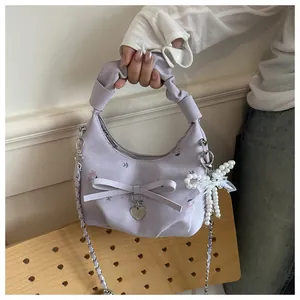 Détail du sac plissé lilas à fleurs avec breloque perle, dentelle et cœur