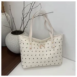 Détail du sac cabas plissé avec imprimé nœuds noirs et ornement en métal doré