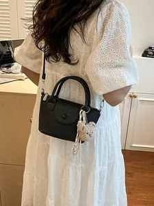 Black litchi grain PU crossbody bag with teddy charm on a white lace dress model