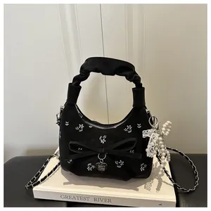 Détails du sac plissé noir avec broderies florales, nœud et pendentif en perles