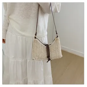 Dettaglio ravvicinato della borsa a tracolla in paglia intrecciata beige con cinturini marroni