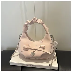 Détail du sac à main fleuri rose avec nœud décoratif, chaîne en perles et pendentif cœur