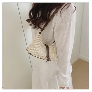 Dettaglio della borsa hobo leggera in paglia intrecciata con tracolla in pelle marrone