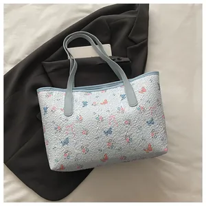 Detailed close-up of light blue floral tote bag with textured butterfly embroidery