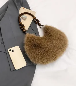 Detailed close-up of brown plush faux fur bag with beaded wooden handle and mobile phone size scale