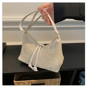 Dettaglio di una borsa hobo intrecciata beige con chiusura a zip e nodi decorativi in pelle