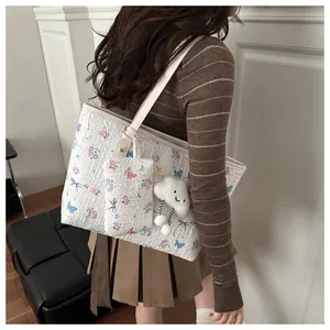 Detail of floral tote bag set with butterfly print and cloud plush charm shown on shoulder
