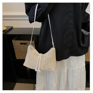 Dettaglio di una borsa a spalla in paglia intrecciata con laccio decorativo bianco crema