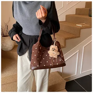 Detail of brown suede polka dot tote bag with a bow and cute plush bear charm