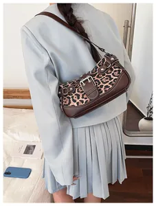 Leopard print baguette bag with brown leather straps shown on shoulder with suit
