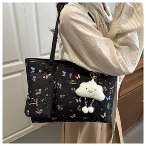 Close-up of black floral tote bag with cloud charm and small matching zipper pouch