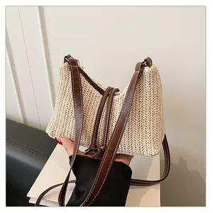 Dettaglio borsa in paglia beige con tracolla in pelle marrone e cuciture a contrasto