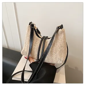 Dettaglio della trama in paglia beige e finiture in ecopelle nera sulla borsa a spalla