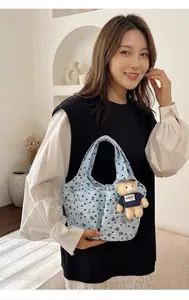 Detalle del bolso tote azul claro con flores de textura burbuja y colgante de osito