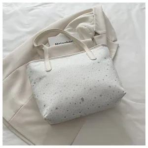 Detail of beige tote bag with silver star prints on a stylish neutral blazer