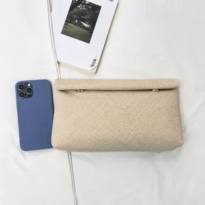 Detailed view of beige woven envelope clutch bag with champagne gold magnetic buckles