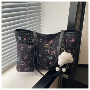 Detail of black tote bag set with floral patterns and a plush cloud charm accessory