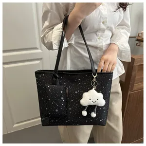 Black polka dot tote bag with a white cloud plush charm worn over the shoulder