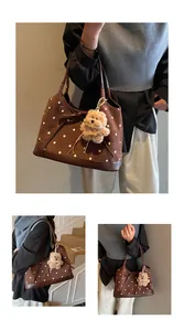 Detail of brown polka dot tote bag with a suede texture, bow knot, and bear charm