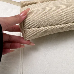 Macro detail of the woven beige clutch bag showing precise stitching and textured fabric