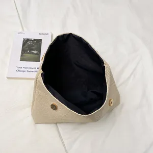 Detail view of woven beige handbag featuring black lining and dual magnetic snap closures