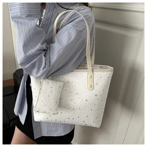 Detailed view of white tote bag with star prints, matching coin purse and leather straps