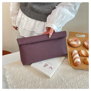 Vue détaillée de la pochette violet foncé avec texture tissée diagonale et rabat