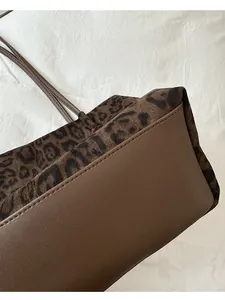 Détail du fond arrondi et des finitions en cuir marron du sac cabas en daim à imprimé léopard