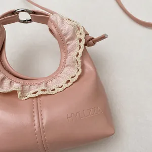 Detail of pink PU leather handbag with lace trim, floral fabric edges, and silver hardware