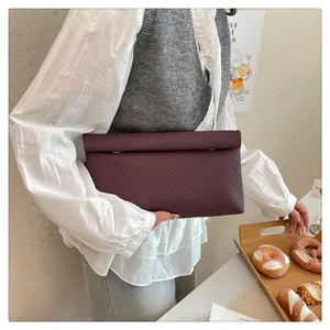 Détail d'une pochette enveloppe tissée violet foncé dans un décor de café élégant