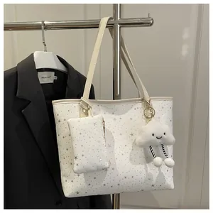 Close-up of white tote bag set with silver star prints and fluffy cloud charm