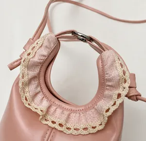 Close-up of pink mini dumpling bag with lace handle and delicate metal hardware