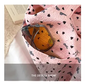 Detalle del bolsillo delantero de un bolso tote rosa con estampados de corazones