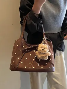 Brown polka dot tote bag with leather bow and bear charm shown in a full lifestyle view