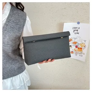 Détail de la pochette enveloppe à carreaux gris foncé avec boutons dorés