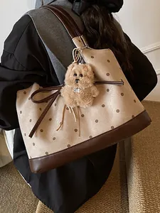 Large polka dot tote bag with plush charm, showing side profile and shoulder strap detail