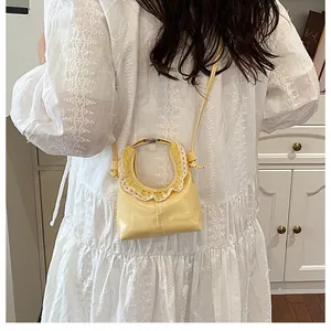 Detail of yellow mini crossbody bag with white lace trim worn on a white dress