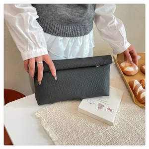 Détail d'une pochette gris foncé avec motif en nid d'abeille tissé et design minimaliste chic