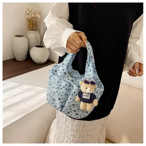 Dettaglio della borsa trapuntata celeste con motivi floreali e ciondolo a forma di orso