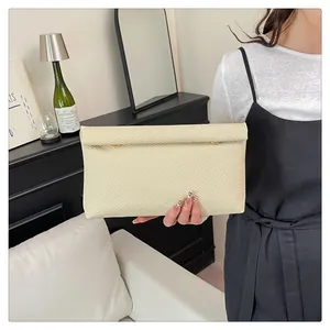 Détail d'une pochette tressée crème avec boucles dorées dans un décor intérieur moderne