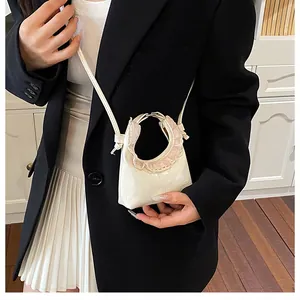 Detail of mini off-white lacquer crossbody bag with pink lace trim and carry handle