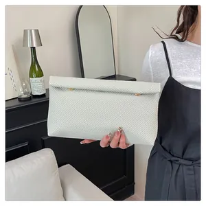 Gros plan d'une pochette tressée blanche avec des boucles métalliques dorées