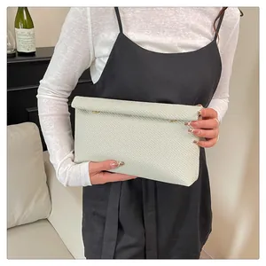 Détail d'une pochette enveloppe minimaliste avec texture tissée et boutons en métal