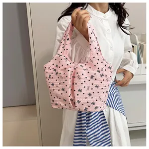 Dettaglio della borsa tote rosa in tessuto trapuntato con cuori tenuta da una modella
