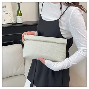 Détail d'une pochette enveloppe tressée vert clair avec des clous dorés